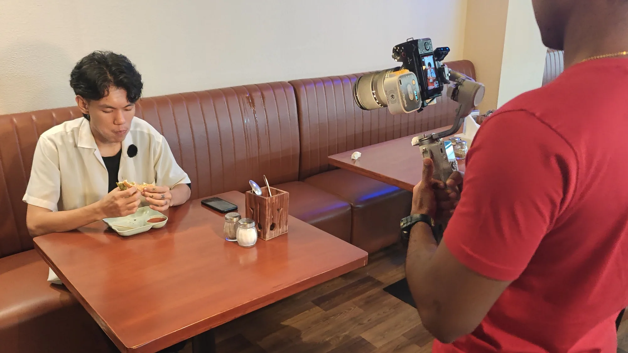 A camera operator filming a customer at a table during a client shoot